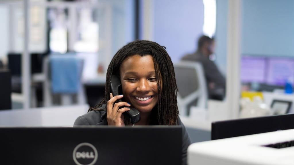 Woman on the phone at her desk looking at her Dell computer screen scheduling a pest control treatment