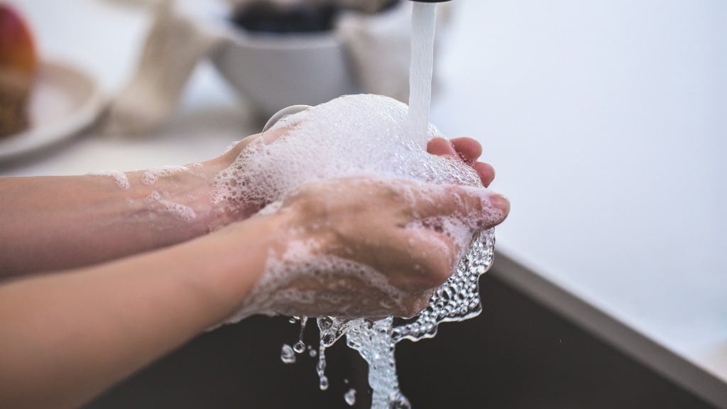 Washing hands under a kitchen sink faucet after a brown recluse spider bite