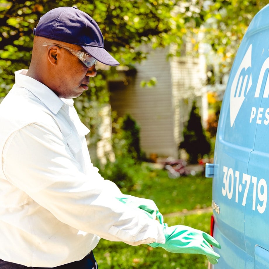moxie pest control technician preparing to treat a customer's home by putting protective gear on